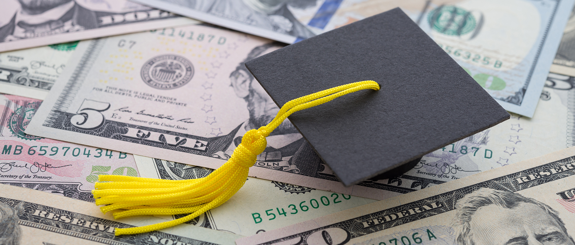 A graduation cap and tassel sitting on top of money
